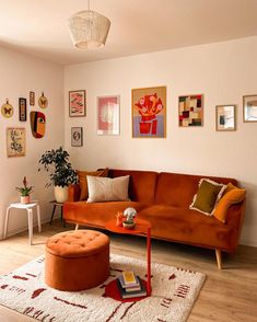 a living room with orange couches and pictures on the wall above it, along with a coffee table