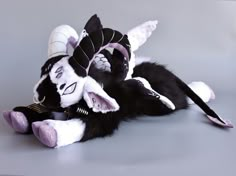 a black and white cat laying on top of a stuffed animal