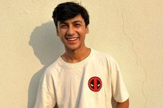 a young man standing in front of a wall wearing a deadpool t - shirt