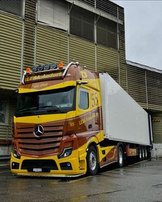 a yellow semi truck parked in front of a building