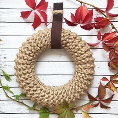 a burlock wreath on a white wall with red leaves around it and a brown leather belt