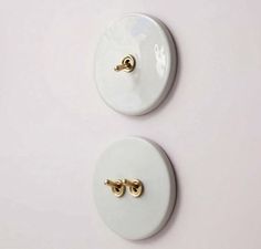 two white buttons with gold handles on a white surface, one is facing the camera