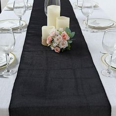 the table is set with white and black linens, candles, and pink flowers