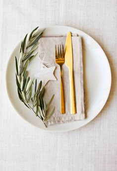 a white plate topped with a fork and knife next to an ornament on top of a napkin