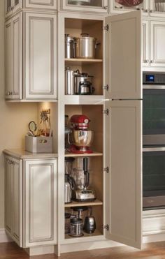 an open cabinet in a kitchen filled with appliances