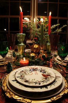 a table set for christmas with candles and plates