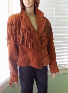 This is a Gorgeous Suede Jacket. It is a suede leather jacket with full fringe around the bodice with padded drop shoulders and bat wing sleeves. This crop jacket has 3 etched metal snaps at the waist and slide in pockets. The sleeve cuffs and back have a decorative cinch tie and a full inside lining. This jacket is in Excellent Condition! Label:     WILSONS THE LEATHER EXPERTS Size:      X Large (Double Check Measurements).  Measurements are taken with the garment LAYING FLAT. Double where appl Fall Leather Tassel Outerwear, Leather Tassel Outerwear For Fall, Winter Leather Outerwear With Tassels, Winter Leather Tassel Outerwear, Fall Leather Outerwear With Fringe, Leather Fringe Outerwear For Fall, Fall Leather Jacket With Tassels And Long Sleeves, Western Style Suede Winter Outerwear, Western Suede Outerwear For Winter