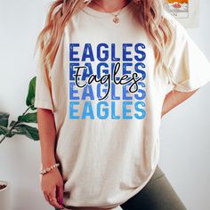 Get this popular new Eagles stacked text shirt and show off your school spirit in style!  Each shirt is printed in-house by me using high-quality materials on a Comfort Colors shirt, known for its exceptional comfort, style, and durability. Available in unisex sizes S to 3X, and youth sizes, we've got you covered regardless of your preferred fit. The Eagles stacked text Shirt features a classic crew neck and short sleeves, making it suitable for year-round wear. The flattering silhouette ensures a comfortable and stylish fit for both men and women. Please note that ivory is ONLY available in Adult sizes!  Note: As each shirt is individually printed, slight variations in color and placement may occur, adding to the uniqueness and charm of your Eagles Shirt. Your shirt will come with care in Eagles Spirit Wear, School Spirit T-shirt With Graphic Print, Blue College T-shirt With Name Print, White Graphic Print Shirt For College Events, Team-colored Cotton Shirt With Letter Print, School Spirit Game Day Shirt With Graphic Print, Blue School Spirit Shirt With Graphic, Collegiate Cotton T-shirt With Name Print, School Spirit Graphic Print Shirt For Game Day