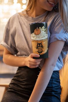 a woman holding up a cup of coffee with an owl on it's sleeve