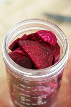 a jar filled with beets sitting on top of a wooden table