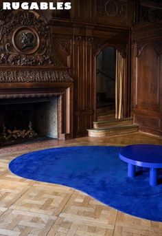 a living room with a fireplace and blue rugs on the floor in front of it