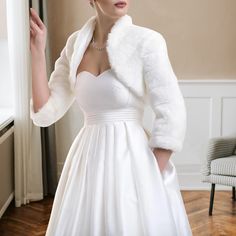 a woman in a white dress and fur stoler posing for the camera with her hand on her hip