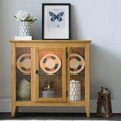 a wooden cabinet with plates and vases on it next to a rug in a room