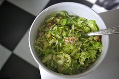 a white bowl filled with lettuce on top of a checkered tablecloth