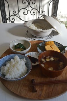 a wooden tray topped with bowls filled with food