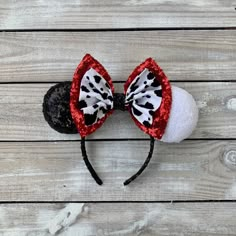 a black and white cat ears hat with red sequins on the top, sitting on a wooden surface