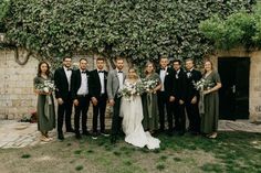 a group of people standing next to each other in front of a wall with ivy growing on it