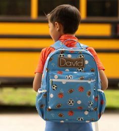 a young boy with a blue backpack is standing in front of a school bus