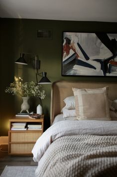 a bedroom with a bed, nightstand and painting on the wall above it's headboard