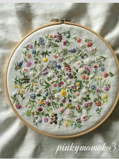 a close up of a embroidery on a white cloth with flowers in the middle and green leaves