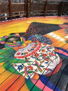 a painted wooden deck with an umbrella and flowers on it