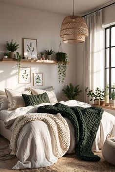 a bed with white sheets and blankets in a room next to a window filled with potted plants