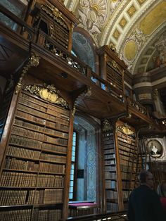 an old library with lots of books on the shelves and people looking at them from below