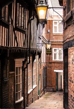 an alley way with brick buildings and a street lamp