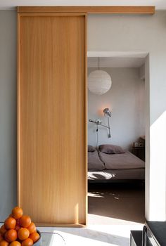 an open door leading to a bedroom with a bed and fruit on the table next to it