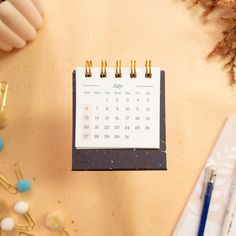 a calendar sitting on top of a desk next to pens and pencils