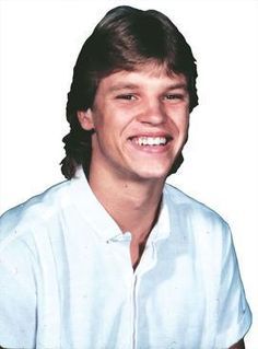 a young man is smiling and wearing a white shirt