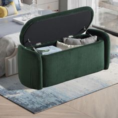 a green storage bench with cushions and pillows on it in a room next to a bed