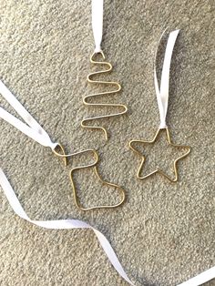 two gold christmas ornaments with white ribbons on the floor next to each other and a star shaped ornament hanging from it