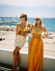 two women standing next to each other near the ocean