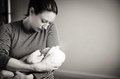 a woman holding a baby in her arms and looking down at it's breast