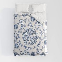 an unmade bed with blue and white flowers on it