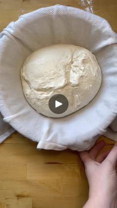 a video demonstrating how to make bread in a paper bag on a wooden table with a person's hand