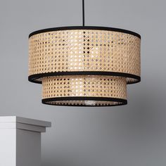 a light that is hanging from a ceiling with wicker covering it's sides