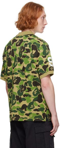 Cotton piqué polo. Camouflage logo pattern printed throughout. · Rib knit spread collar and cuffs · Two-button placket · Logo graphic embroidered at front · Vented side seams · Text applique at sleeves Supplier color: Green Logo Pattern, Collar And Cuff, Logo Graphic, Button Placket, Camouflage, Rib Knit, Camo, Print Patterns, Abc