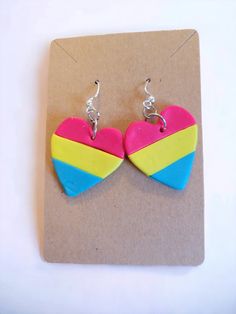 two colorful heart shaped earrings are on a piece of brown paper next to a pair of silver earwires