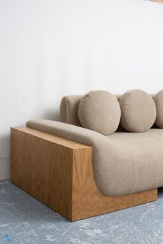 a couch sitting on top of a wooden table next to a wall with three round pillows