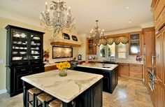 a large kitchen with marble counter tops and black cabinets