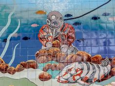 a mural on the side of a building depicts a man in a diving suit and fish