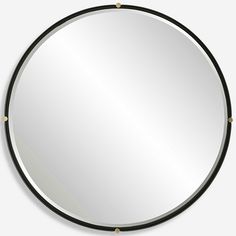 a round mirror sitting on top of a white wall next to a black and gold frame