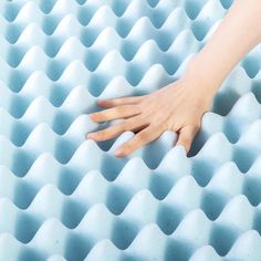 a person's hand on top of a foam mattress