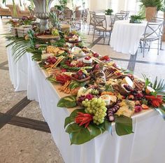 a long table filled with lots of food and greenery on top of white clothed tables