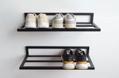 three pairs of shoes are sitting on two black shelving shelves, one is empty