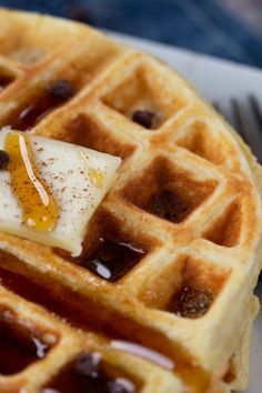 waffles with syrup and butter on top sitting on a plate next to a fork