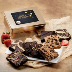 some brownies and strawberries are on a white plate next to a box of dolcet