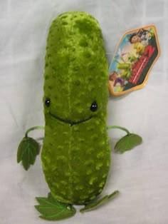 a green stuffed toy sitting on top of a white sheet